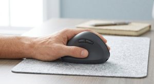 A left hand on a left-handed ergonomic mouse with side buttons where the thumb rests