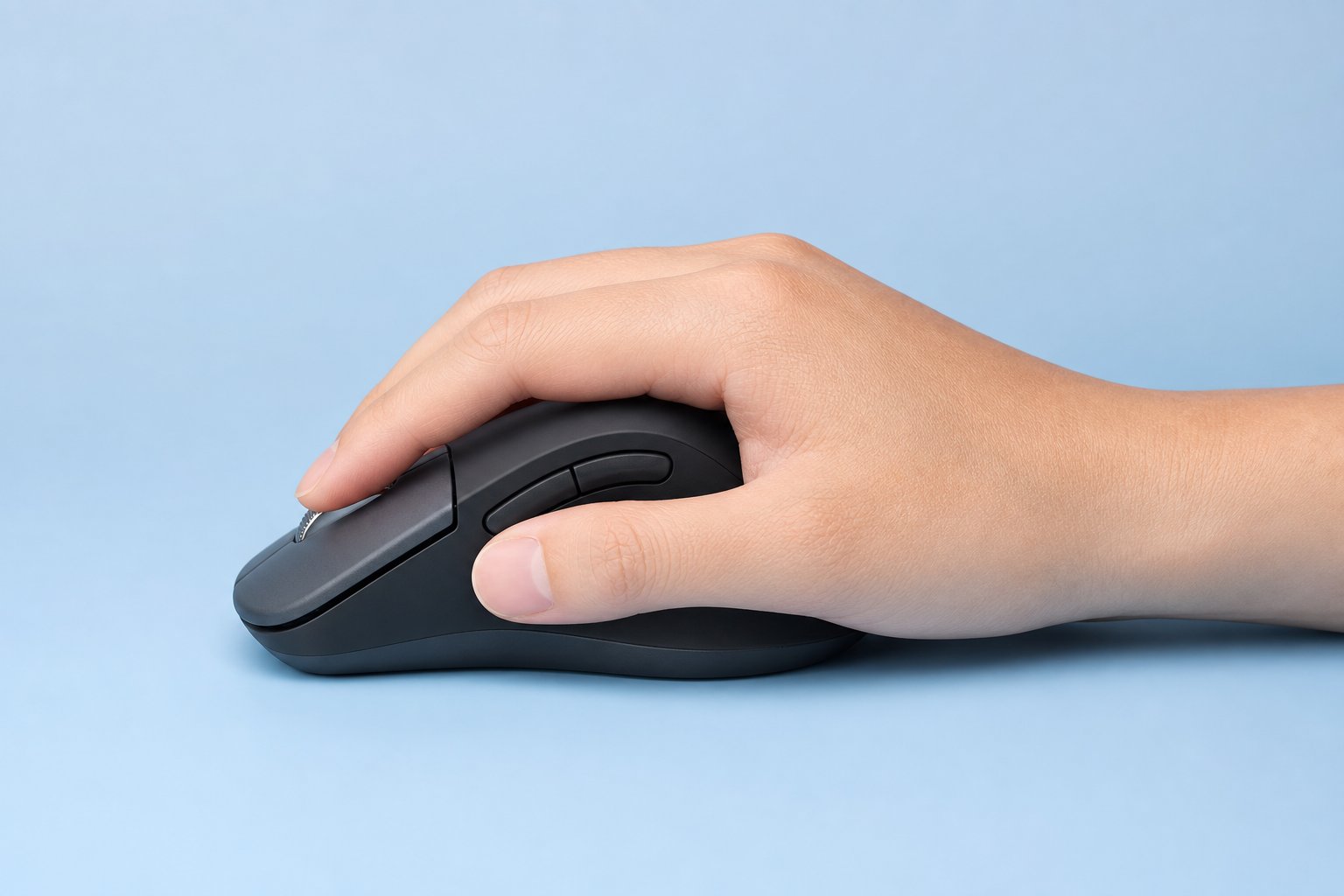 A hand resting on a computer mouse in a palm grip on a light blue background